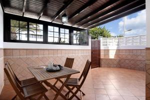 Un patio con una mesa y sillas de madera. en Apartamento White Sun, en Playa Honda