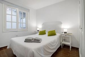- une chambre blanche avec un lit blanc et des oreillers verts dans l'établissement Apartamento White Sun, à Playa Honda