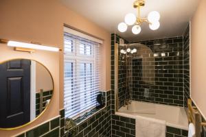 a bathroom with black tiles and a mirror at The Old Coach House, Gorgeous 3 Bed, Central, Modern, Parking, King Bed, HUGE Bath in Yeovil