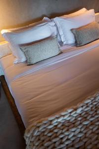 a bed with white sheets and pillows on it at Paru Boutique Hotel in São Miguel dos Milagres