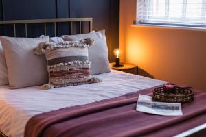 a bed with a pillow on it with a table at The Old Coach House, Gorgeous 3 Bed, Central, Modern, Parking, King Bed, HUGE Bath in Yeovil