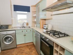 a kitchen with a stove and a washing machine at Dulas in Llandudno Junction
