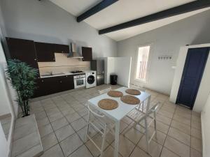 a kitchen with a white table and chairs in it at Le Rempart in Saint-Mitre-les-Remparts