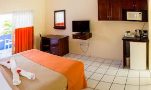 a bedroom with a bed and a desk and a tv at Bay Gardens Inn in Gros Islet