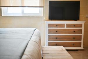 Un dormitorio con un tocador con TV. en Ogygia Suites Gozo, en Għarb