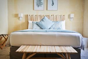 1 dormitorio con cama grande y banco de madera en Ogygia Suites Gozo, en Għarb