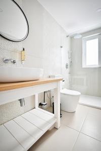 a white bathroom with a sink and a toilet at Ogygia Suites Gozo in Għarb