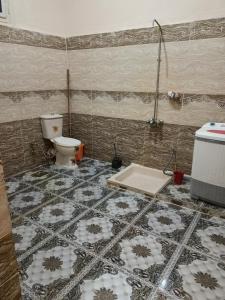 a bathroom with a toilet and a tiled floor at Dakrour flat in ‘Izbat Ţanāţī