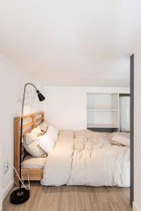 biała sypialnia z łóżkiem i lampką w obiekcie Le Mélodie w mieście Saint-Étienne