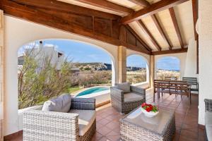 an outdoor patio with chairs and a table and a pool at Binizzy in Cala Morell