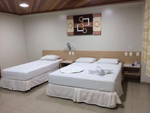 two beds in a hotel room with at Swamy Hotel in Cruzeiro do Sul