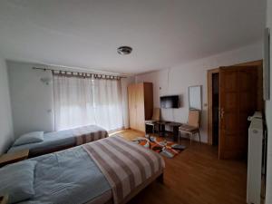 Privatni smještaj Tolić في Ladimirevci: غرفة نوم بسريرين ومكتب وتلفزيون