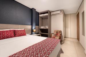 um quarto com uma cama com almofadas vermelhas e uma cadeira em 103 Hotel & Flats em Palmas