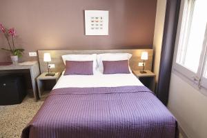 a bedroom with a large bed with purple sheets and pillows at Hostal Fonda Montserrat in Cambrils