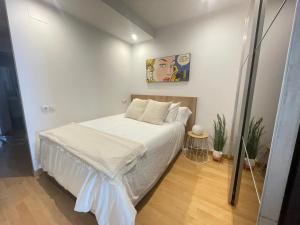 a small bedroom with a bed with white sheets at Loft en el mercado del Fontan in Oviedo