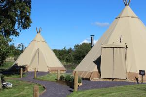 two large teepees in a park with a blue sky at GreenWood Family Park in Y Felinheli