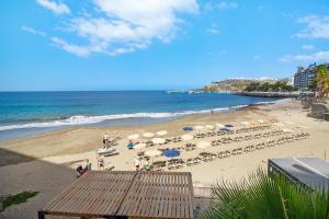 una spiaggia con sedie, ombrelloni e persone di Articel Patalavaca a Patalavaca