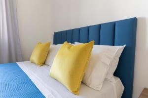 1 cama con almohadas amarillas y almohadas azules y blancas en Tenuta Di Leva, en Piano di Sorrento