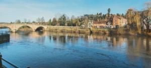 斯托波特的住宿－Waters Edge, Town house in Stourport-on-Severn，一座河上的桥梁,有房子和城市