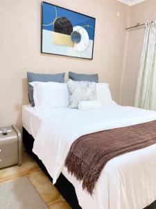 sypialnia z dużym białym łóżkiem w pokoju w obiekcie Ranzi Court Guest House w mieście Palapye