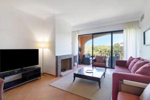 Una sala de estar con un sofá y un televisor. en Apartamento T2 Vilasol Morgadinho, en Vilamoura