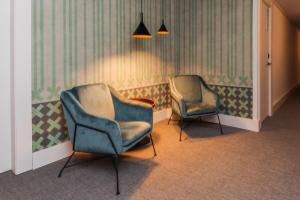 2 Stühle in einem Zimmer mit grüner und weißer Tapete in der Unterkunft Hotel Lauria in Tarragona