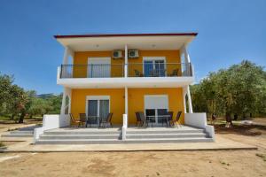 una gran casa amarilla con mesa y sillas en Platana Studios Karadolas en Skala Rachoniou