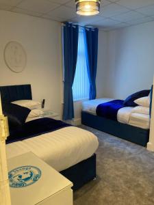 two beds in a room with blue curtains at The New Apollo Hotel in Blackpool