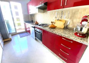 eine Küche mit roten Schränken und einer Arbeitsplatte in der Unterkunft Cosy and greeny flat near oasis train and tramway in Casablanca