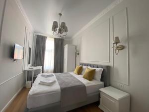 a white bedroom with a large bed with yellow pillows at Pensiunea Korona in Miercurea-Ciuc