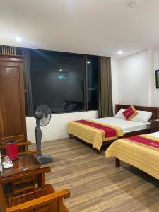 une chambre d'hôtel avec deux lits, une table et une lampe dans l'établissement Khách sạn An Phú Cửa Lò, à Cửa Lô