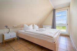 a bedroom with a large white bed with a window at Ferienappartement Müritzblick in Vipperow