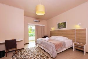 a bedroom with a bed and a desk and a window at Hotel Fazenda Dona Francisca in Joinville