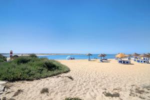 een strand met parasols en stoelen en de oceaan bij Casa Anzol in Fuzeta