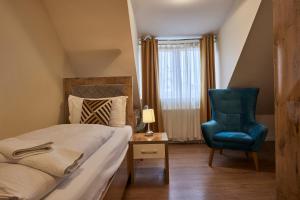 a bedroom with a bed and a blue chair at Hotel Isha in Frankfurt/Main