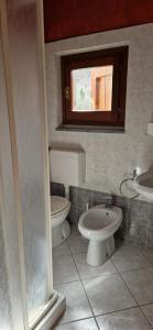 baño con 2 aseos, lavamanos y ventana en Casa Carda di Lai Loretta, en Castel Focognano