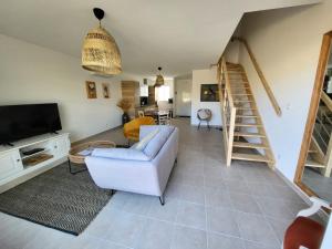 a living room with a couch and a tv and stairs at L'Hirondelle Blanche - 4 étoiles in Dolus d'Oléron