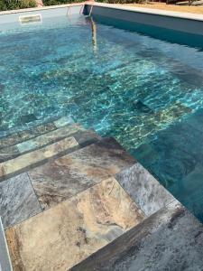 d'une piscine d'eau bleue et de carrelage. dans l'établissement Villa sud de la France avec piscine privée, à Les Fumades-Les Bains