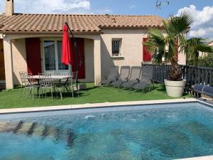 - une piscine en face d'une maison avec une table et des chaises dans l'établissement Villa sud de la France avec piscine privée, à Les Fumades-Les Bains