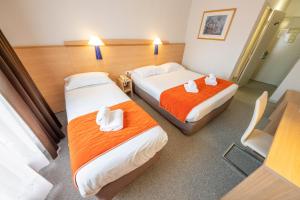a hotel room with two beds with orange sheets at Hôtel Saint Laurent in Nogent-sur-Seine +62 photos