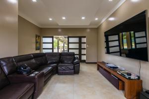 a living room with a leather couch and a flat screen tv at Villa Belle in Egmont