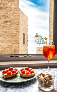 two pizzas on a table with a drink and a window at Dimora nel Palazzo Ducale in Giovinazzo
