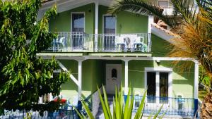 een groen huis met stoelen op het balkon bij Nadia's Beach House in Pefkari