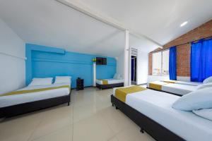 1 dormitorio con 2 camas y pared azul en Hotel Confort Obelisk, en Medellín