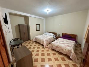 Habitación con 2 camas y mesa. en Hostal Trumarka, en Cajamarca