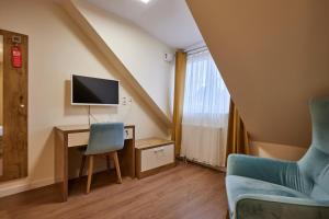 Zimmer mit einem Schreibtisch, einem TV und einem Stuhl in der Unterkunft Hotel Isha in Frankfurt am Main