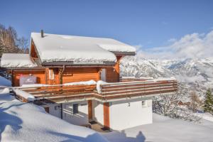 una casa cubierta de nieve con montañas en el fondo en Chalet le Fauconnier, en La Tzoumaz