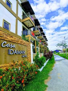 un panneau sur le côté d'un bâtiment avec des fleurs dans l'établissement Casa Idaman Motel, à Pantai Cenang