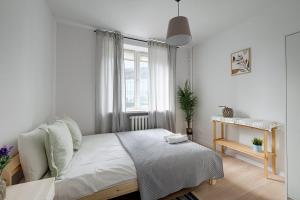 a white bedroom with a bed and a window at Urban Oasis Private Apartment with Palace of Culture View in Warsaw