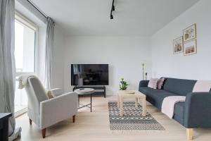 a living room with a blue couch and a tv at Urban Oasis Private Apartment with Palace of Culture View in Warsaw
